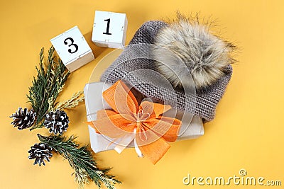 Christmas gift with yellow bows in winter gray hat, numbers three and one on yellow background, top view, space for text Stock Photo