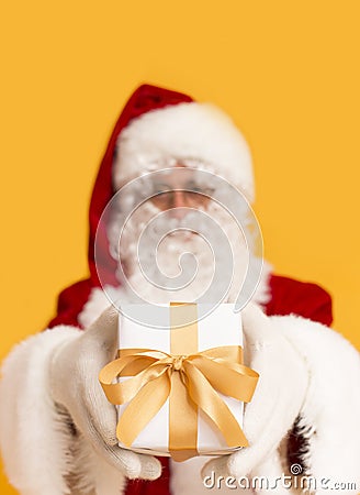 Blurred Santa Claus holding holiday present over orange Stock Photo