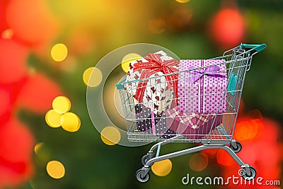 Christmas gifts and presents ribbon gift box in shopping trolley cart with blurred lights Stock Photo