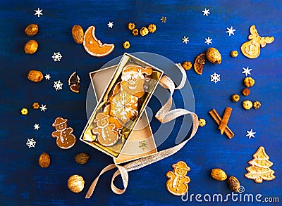 Christmas gingerbread cookies in gift box, ingredients, seasonal decor on deep blue paper background, flat lay Stock Photo