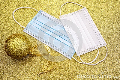 Christmas golden decorative ball on golden background with two surgical protective masks: for adult and for child. New year on Stock Photo