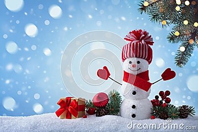 Christmas greeting card with funny snowman, gift box and fir tree branches in winter scenery. Snowy background Stock Photo