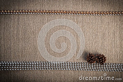 Christmas greeting card with two pine cones and silver-golden beads over linen background Stock Photo