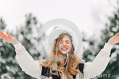 Woman in warm winter clothes, Winter woman blowing snow in the park, throwing snow into the air on a sunny winter day Stock Photo