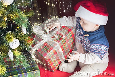 Christmas holiday. Baby in Santa hat opening box of gifts Stock Photo