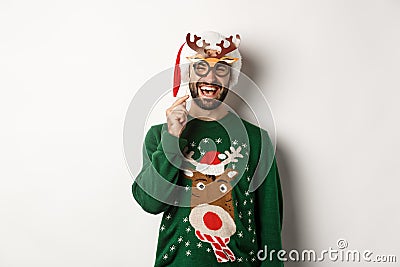 Christmas and holidays concept. Smiling beared man in Santa hat looking happy, holding party mask for New Year Stock Photo