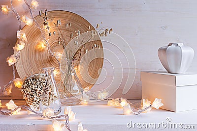 Christmas home decoration with burning lights on white wooden background. Stock Photo