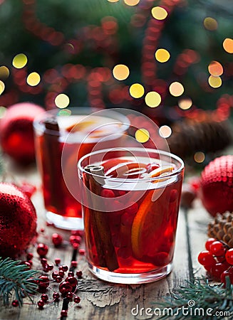 Christmas hot cranberry tea, orange pomegranate punch or mulled wine in a rustic wooden table. Closeup. Stock Photo