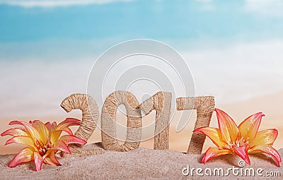 Christmas inscription 2017 in sand decorated with tropical flowers on a background of the sea Stock Photo