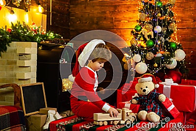 Christmas Kids concept. Happy kid is playing with Christmas toys on Christmas tree background. Kid is waiting for the Stock Photo