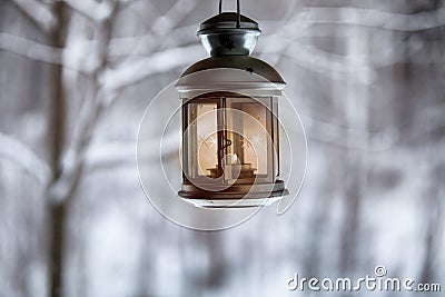 Christmas lantern with candles hanging on a winter landscape background. Stock Photo