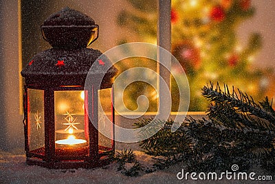Christmas lantern in fornt of a window on a snowing night Stock Photo