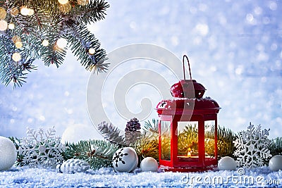 Christmas lantern in snow with fir tree branch and holiday decorations. Winter cozy scene Stock Photo