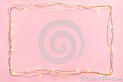 Christmas lights garland border over pink background. Flat lay, copy space. Stock Photo