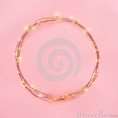 Christmas lights garland circular border over pink background. Flat lay, copy space. Stock Photo