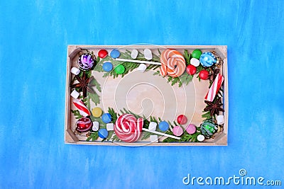 Christmas lollipops, sweets of different colours, marshmallows and thuja branches framing copy space Stock Photo