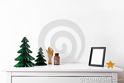 Christmas mock up with black frame and Honeycomb tree paper decor. Square frame on a wooden shelf against a white wall Stock Photo