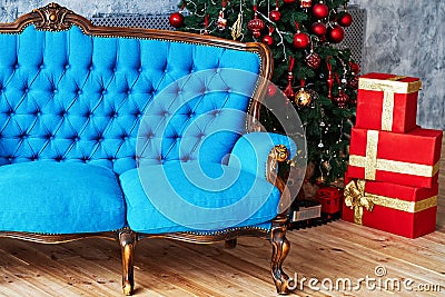 Christmas morning, copy space. Classic apartments with blue buttoned sofa, decorated fir tree and red gift boxes. Stock Photo