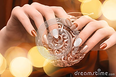 Christmas nail design. Female hands with red and golden manicure. Female hold golden xmas toy orb. Happy New Year Stock Photo