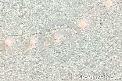 Christmas New Year Background. Diagonal Hanging Pastel Golden Cotton Balls Garland White Wall Background. Scandinavian Style Stock Photo