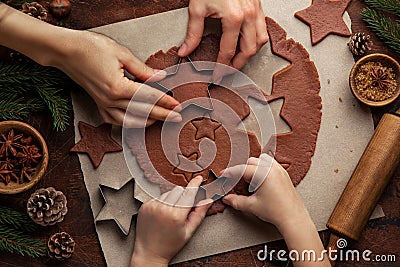 Christmas and New Year bakery. Close up of kids and female hands cooking traditional gingerbread cookies. Wooden kitchen table Stock Photo