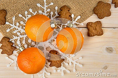 Christmas or New Year tangerines and gingerbread cookies with snowflakes framed on brown sack background texture. Stock Photo