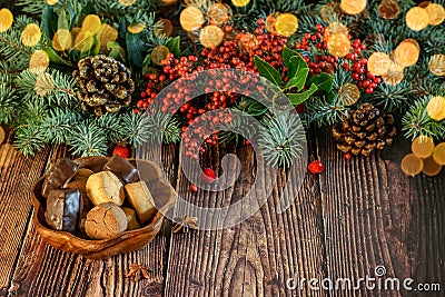 Christmas and New Year vignette of branches of blue fir, pinecones and red berries with a plate of cookies on the wooden natural Stock Photo