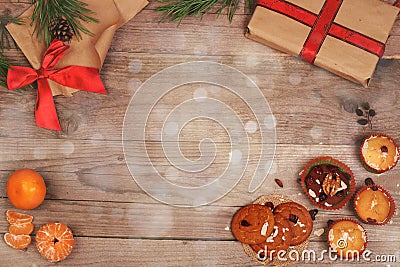 Christmas and New Year wooden background with gifts, bow, tangerines and cupcakes Stock Photo