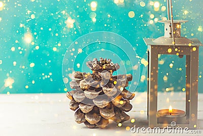 Christmas New Years greeting card with pine cone lantern with burning candle golden garland lights on turquoise background Stock Photo