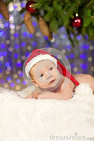 Christmas newborn baby in santa hat. Winter child on winter wonderland background of blurred lights Stock Photo