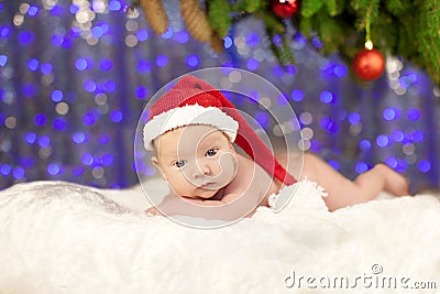 Christmas newborn baby in santa hat. Winter child on winter wonderland background of blurred lights Stock Photo