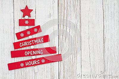 Christmas Opening Hours sign on red wood Christmas tree with weathered wood Stock Photo