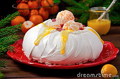 Christmas Pavlova cake with whipped cream, curd, tangerines and pomegranate on a dark wooden background. Copy space Stock Photo