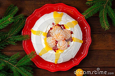 Christmas Pavlova cake with whipped cream, curd, tangerines and pomegranate on a dark wooden background. Copy space Stock Photo