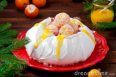 Christmas Pavlova cake with whipped cream, curd, tangerines and pomegranate on a dark wooden background. Copy space Stock Photo