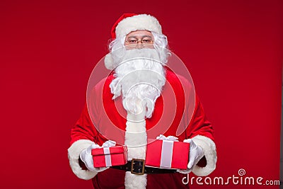 Christmas. Photo Santa Claus giving xmas present and looking at camera, on a red background Stock Photo