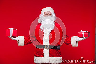 Christmas. Photo Santa Claus giving xmas present and looking at camera, on a red background Stock Photo