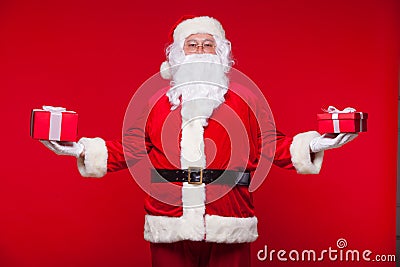 Christmas. Photo Santa Claus giving xmas present and looking at camera, on a red background Stock Photo