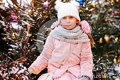 christmas portrait of happy child girl walking outdoor, snowy winter decorated trees on background. Stock Photo