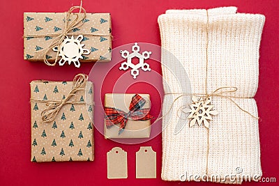 Christmas presents on red background. Kraft paper gift boxes, knitted scarf wrapped in twine, decorative snowflakes. Xmas and Happ Stock Photo