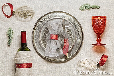 Christmas rustic table setting, bright tableware, red wine glass, plate, knife, fork, wine bottle, glass Christmas Stock Photo