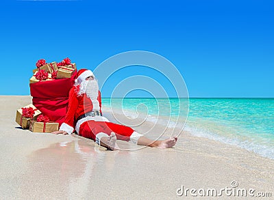 Christmas Santa Claus with gift boxes sack at tropical beach Stock Photo