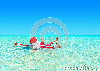 Christmas Santa Claus relax swimming in ocean turquoise transparent water. Stock Photo