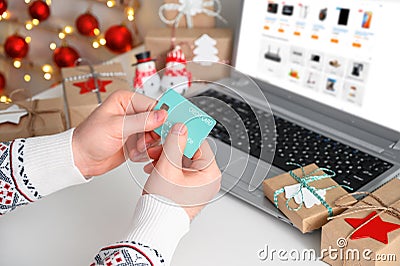 Christmas shopping online. Unrecognizable Man Hands holding Credit Card buying presents by using laptop. Stock Photo