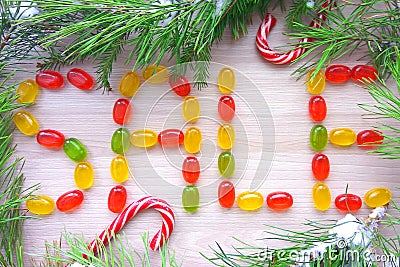 Christmas sign sale made from caramel candies with snowy fir tree branches on wooden background Stock Photo