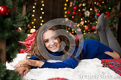 Christmas smiling woman model. Makeup. Healthy long hair style. lady over christmas tree lights background. happy new year Stock Photo