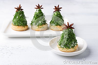 Christmas snack in the form of trees. Delicious cream cheese canapes with nuts, garlic and chopped dill on homemade puff cookies, Stock Photo