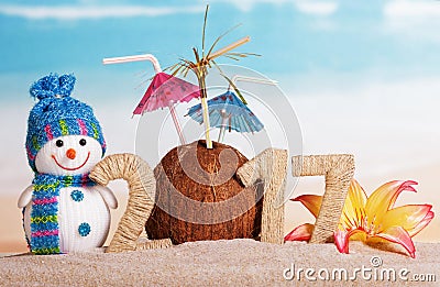 Christmas snowman, coconut with umbrellas and the inscription 2017 in sand against the sea Stock Photo