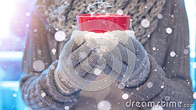 Christmas snowy winter background - Young pretty woman with gloves and scarf stands outdoor and holds a hot steaming teacup in her Stock Photo