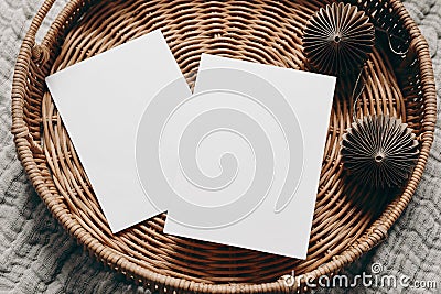 Christmas stationery. Closeup of empty greeting cards, invitation mockups on wicker tray. Brown folded paper Christmas Stock Photo
